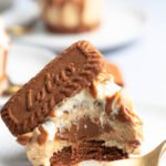 Angebissener Mini-Lotus-Käsekuchen mit cremigen Schichten und einem reichhaltigen Lotus Biscoff Kern, garniert mit Schlagsahne und einem Lotus-Keks.